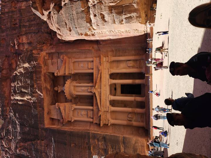 Crowds gather at the ornate sandstone façade of the Treasury in Petra carved into a cliff