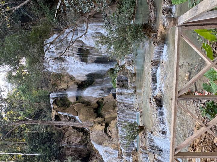 Multi-tiered tropical waterfall cascading into turquoise pools framed by forest.