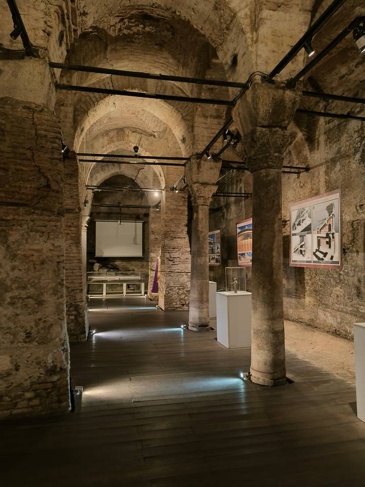 Ancient stone columns and vaulted ceilings form an atmospheric underground museum exhibit.