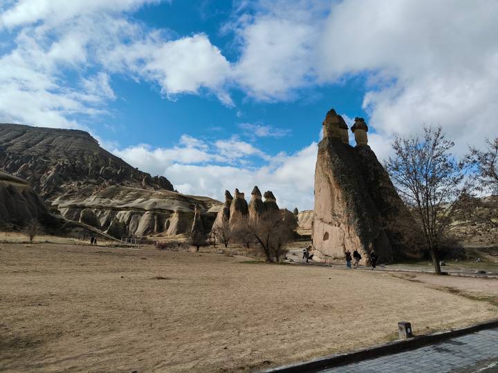 Wide valley of distinctive fairy chimneys and eroded rock formations under a blue sky in Cappadocia.
