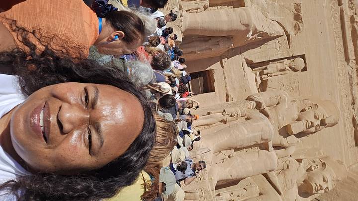 Selfie in front of the colossal seated statues of Abu Simbel surrounded by a crowd of tourists.