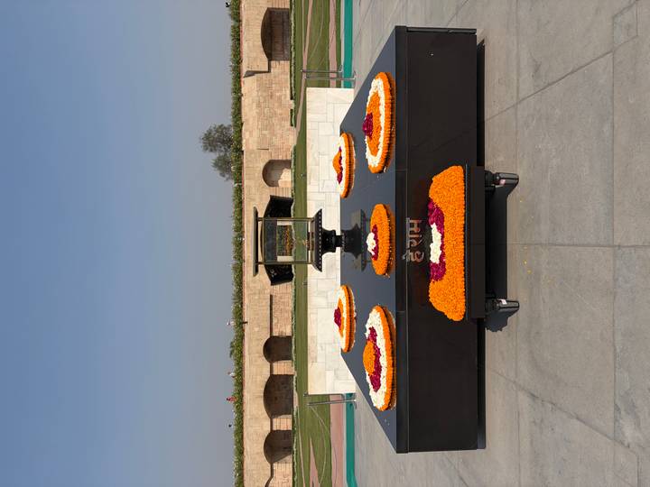 Gandhi memorial platform adorned with vibrant marigold flower arrangements under clear sky.