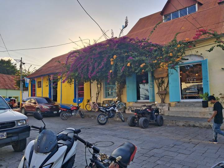 Colorful colonial street in Flores with flowering vines and parked motorbikes at dusk.
