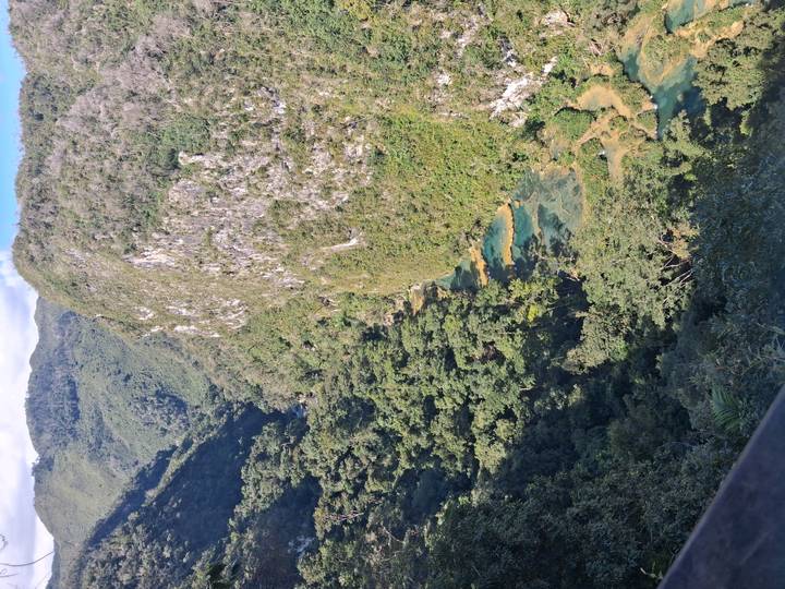 Scenic canyon walls and turquoise stepped pools of Semuc Champey viewed from above.