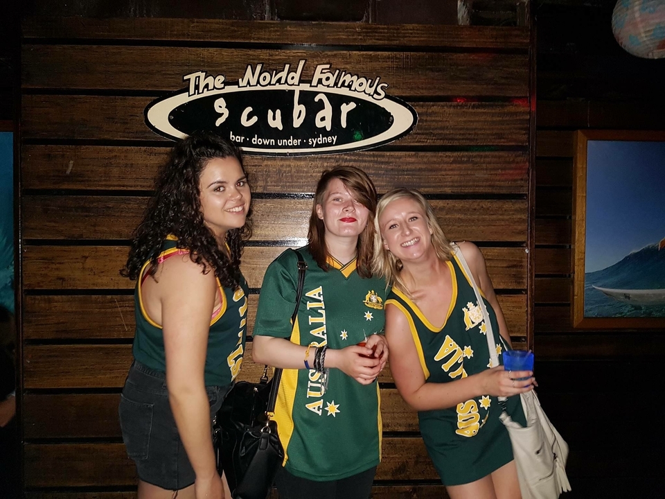 Three women posing in front of a venue sign in Sydney.