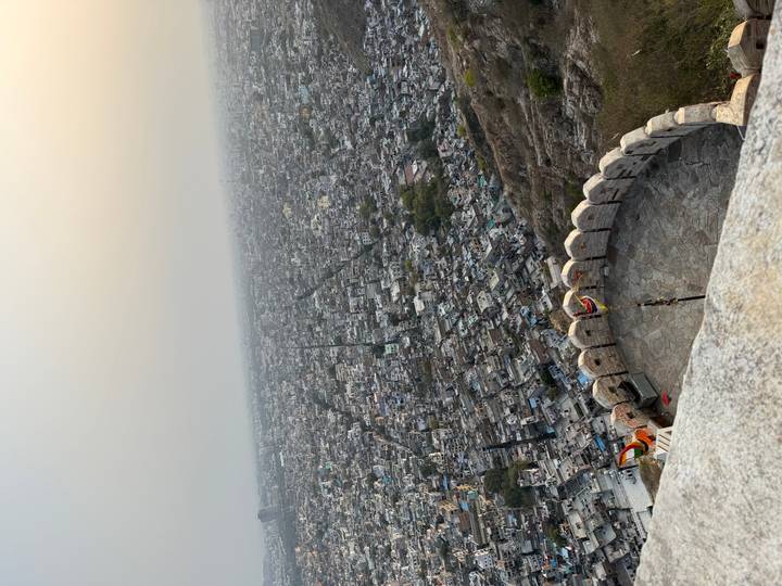 Hazy panoramic cityscape stretching to the horizon seen from a high fort bastion with fluttering flags