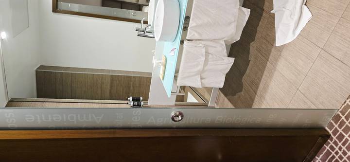 Modern hotel bathroom with towels hanging untidily and one lying on the floor.