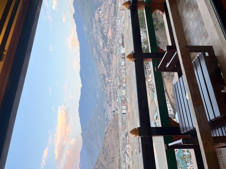 Balcony seating area overlooking Paro valley, mountains and bright blue sky in late afternoon.
