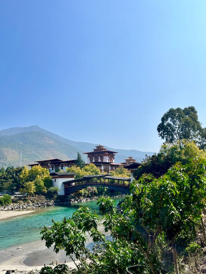 Elegant Punakha Dzong and its traditional wooden bridge set against forested Bhutanese hills.