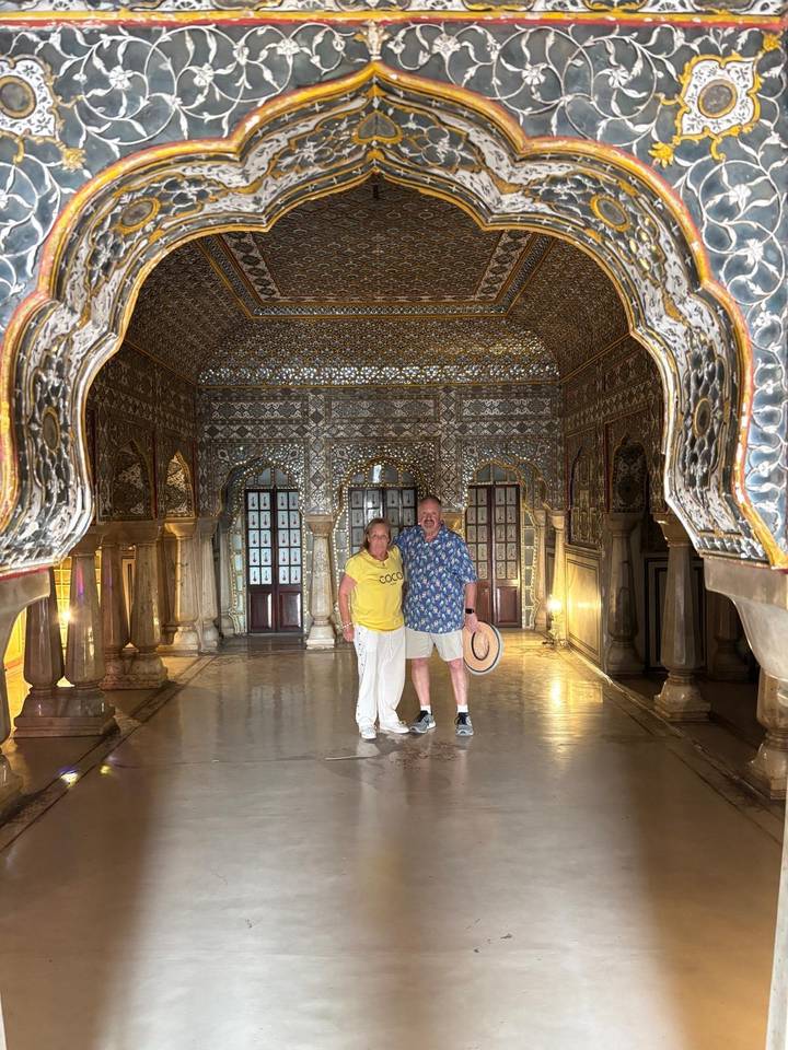 Couple standing inside the glittering Sheesh Mahal mirror hall at Amer Fort.