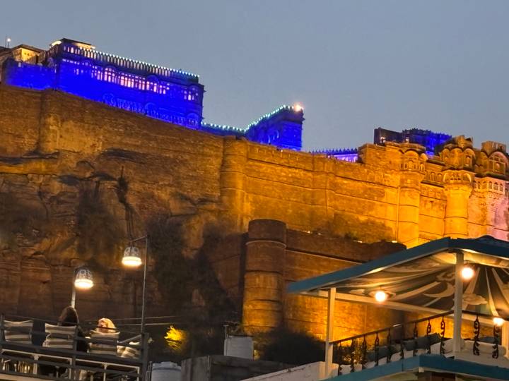 Night view of the illuminated Mehrangarh Fort walls glowing blue and gold above Jodhpur.