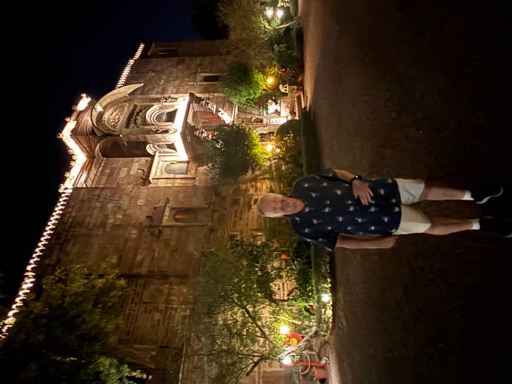 Traveller poses in front of a dimly lit heritage fort entrance at night in Rajasthan.