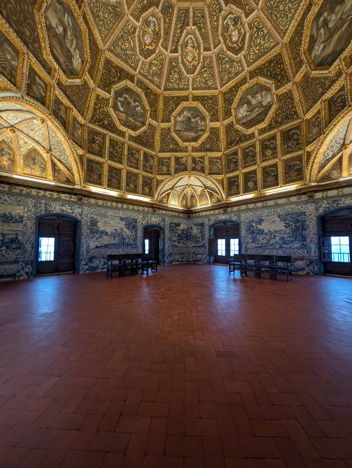 Grand hall lined with blue-and-white azulejo tiles beneath a gilded vaulted ceiling.