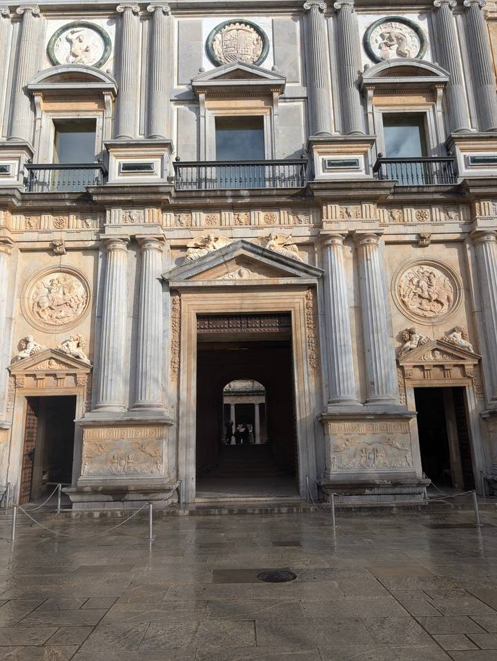 Classical stone entrance with Corinthian columns and sculpted medallions lit by warm sun.