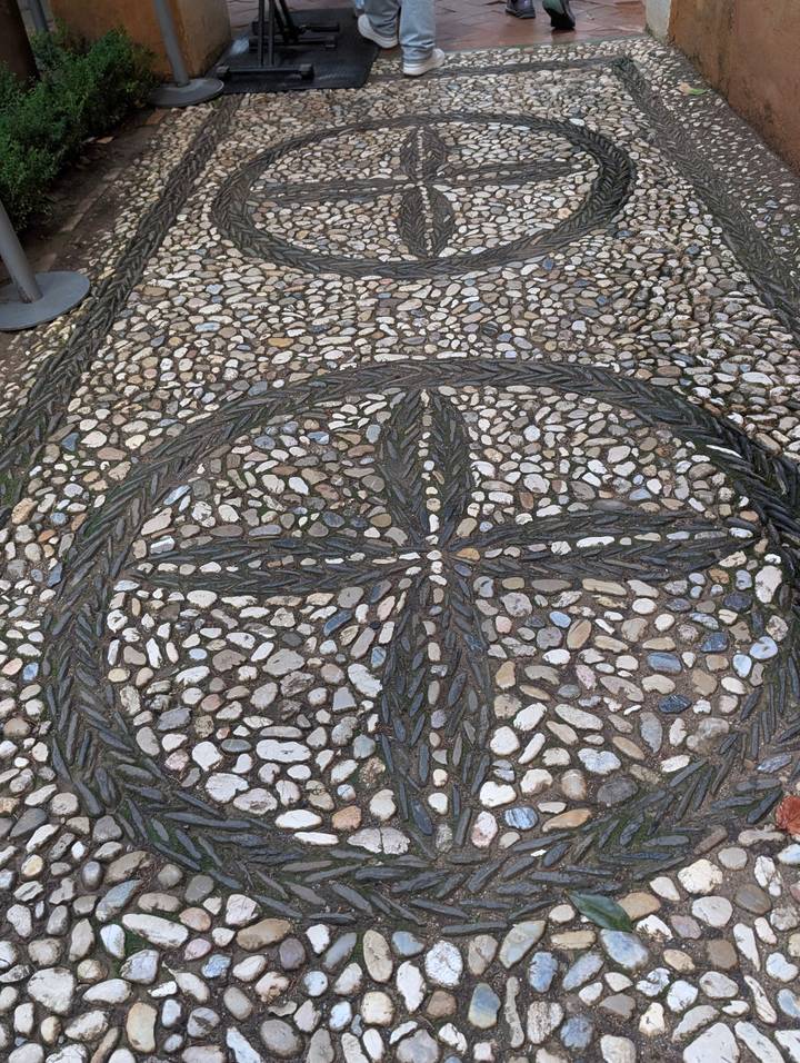Pebble mosaic pavement forming an ornate circular cross pattern.
