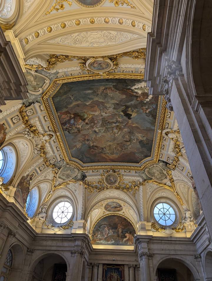 Spectacular frescoed ceiling framed by gilded stucco and arched windows.