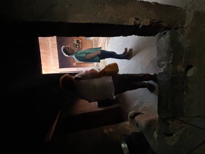 Dimly lit traditional adobe interior with two tourists exploring narrow passageways