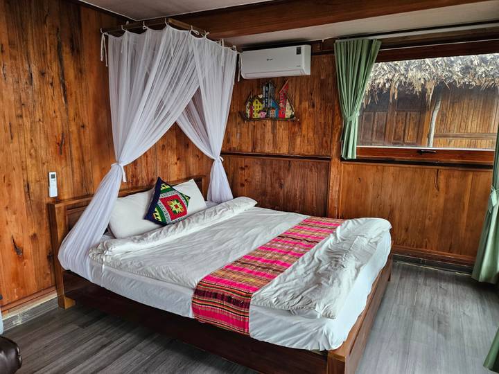 Cozy wooden guest-room with canopy bed, tribal pillow and bright textile runner