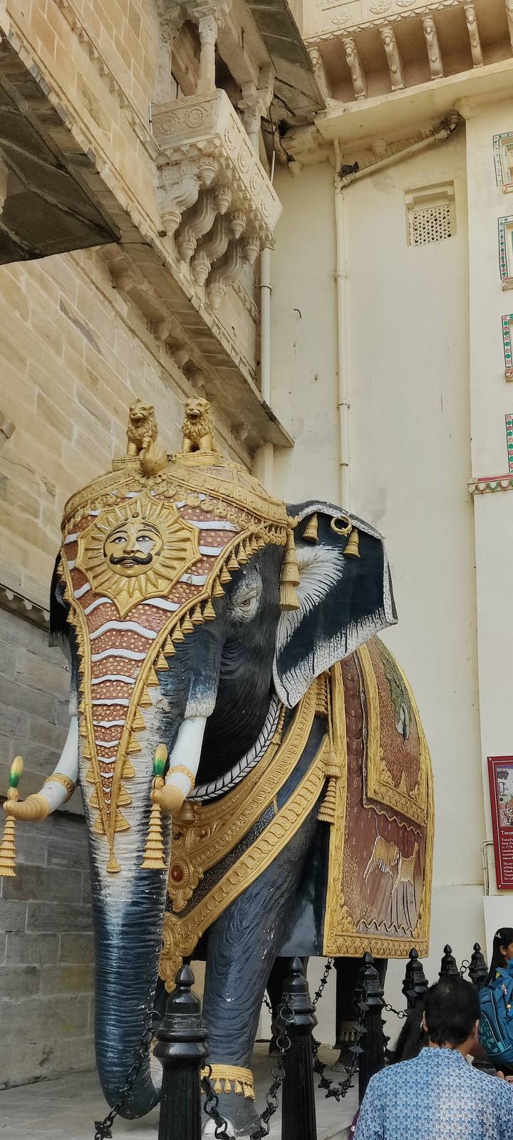 Decorative stone elephant sculpture with painted sun motif and gilded tassels