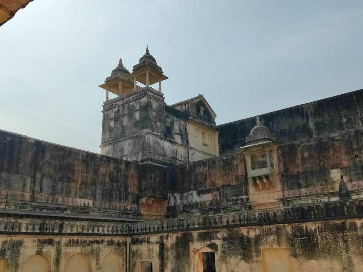 Weather-worn fort tower with peeling plaster under a pale sky