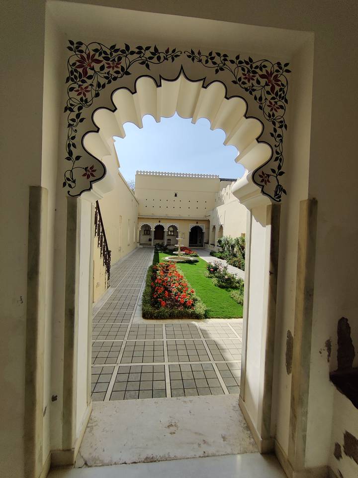 Elegant courtyard garden bordered by cream palace walls and colourful flower beds