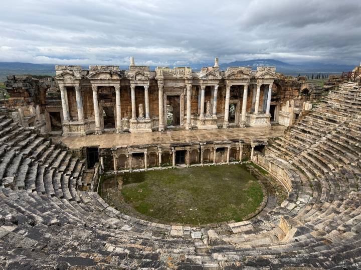 Panoramic view of a well-preserved Roman amphitheatre surrounded by hills.