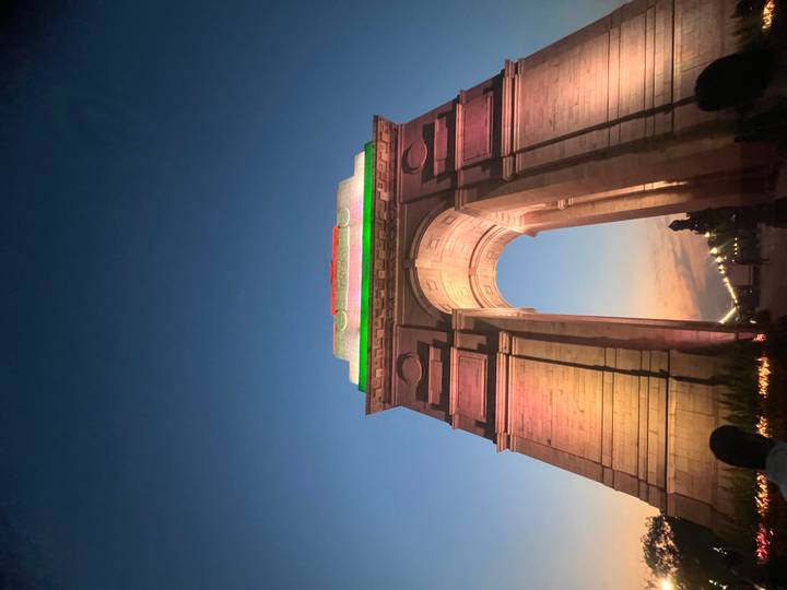 India Gate illuminated in tricolour lights rises against a deepening dusk sky in New Delhi.