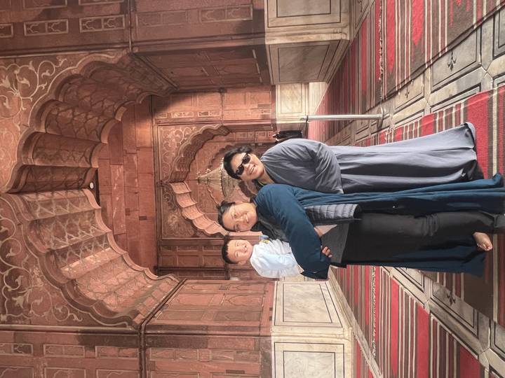 Family group smiles for the camera inside the richly patterned interior of a historic mosque.