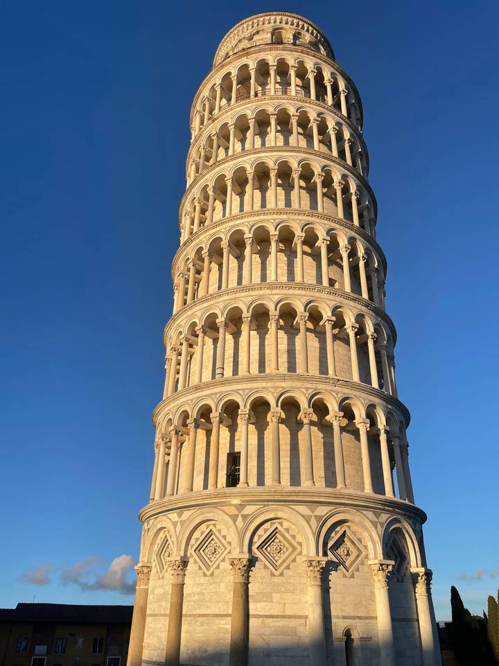 Close-up view of the Leaning Tower of Pisa against a deep blue evening sky