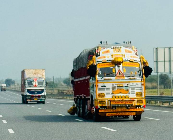 Colorfully painted Indian freight trucks driving along a highway.