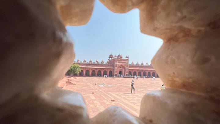 Creative peek through carved stone lattice framing the courtyard of Fatehpur Sikri.