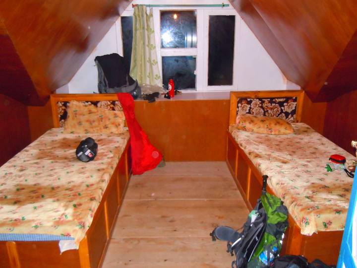 Simple accommodation with two single beds and some personal items.
