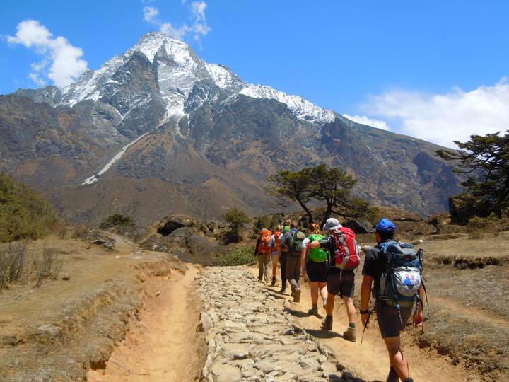 Hikers walking along a path with a snowy mountain in the background.