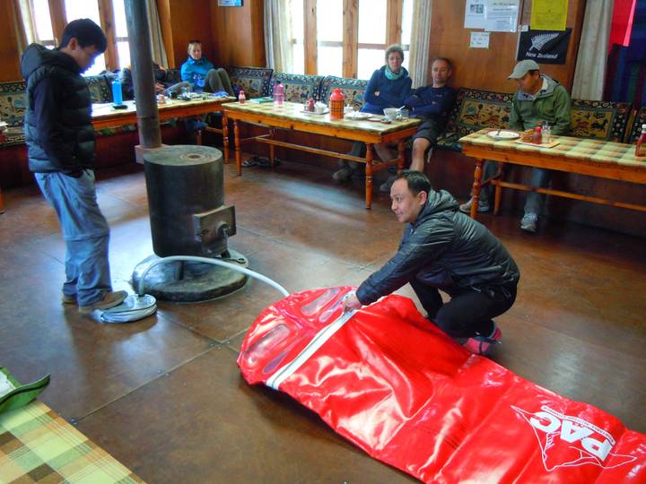 People inside a room with a stove and red equipment being set up.