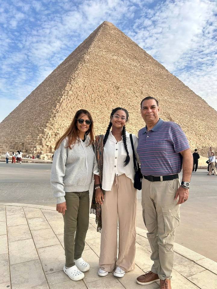 Family standing before the massive Great Pyramid of Giza on a clear afternoon.