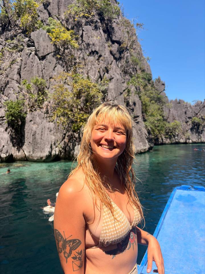 Young woman smiling on a boat in a turquoise lagoon surrounded by dramatic limestone cliffs