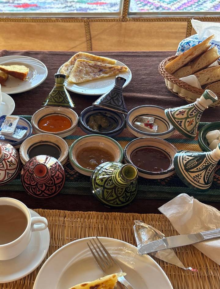 Traditional Moroccan ceramic bowls with various sauces and mini tagine lids set on a table.