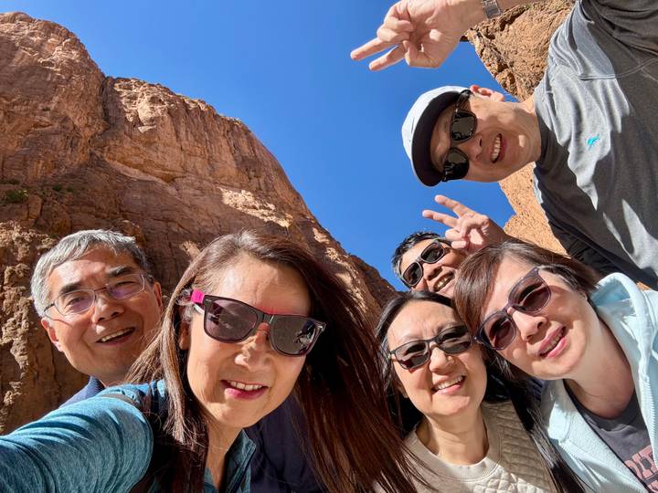 Group selfie wearing sunglasses with towering canyon walls behind.