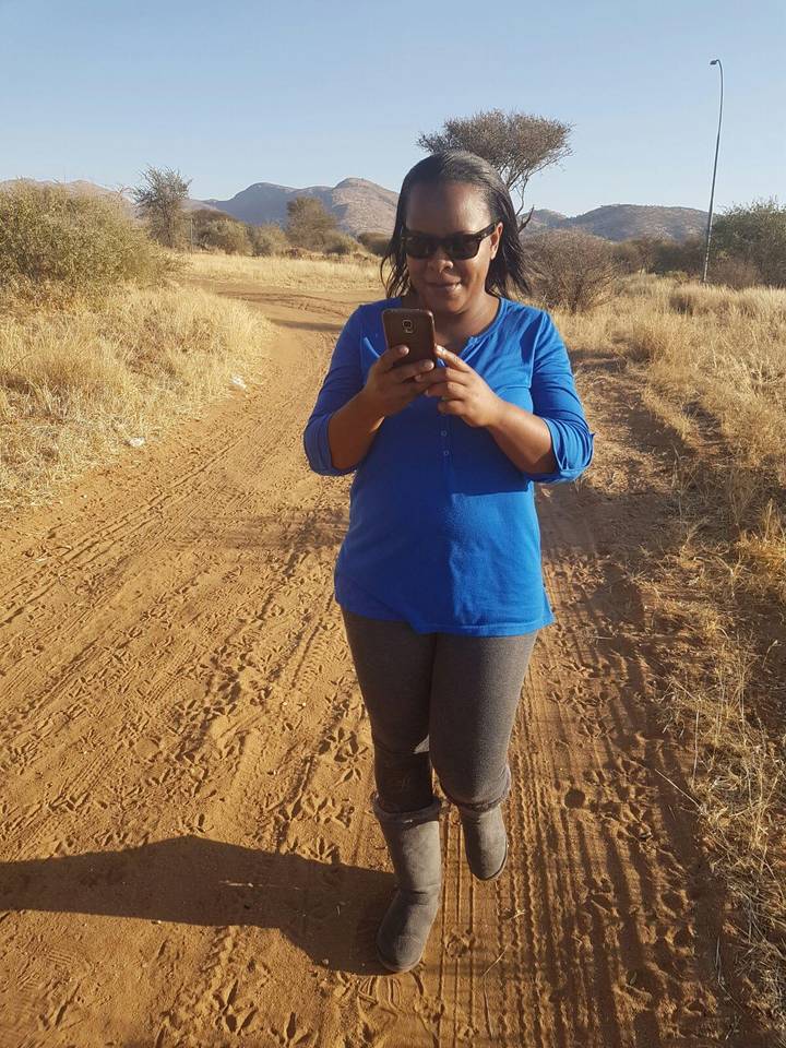 Close-up of a traveler taking a photo with a smartphone on a dirt path.