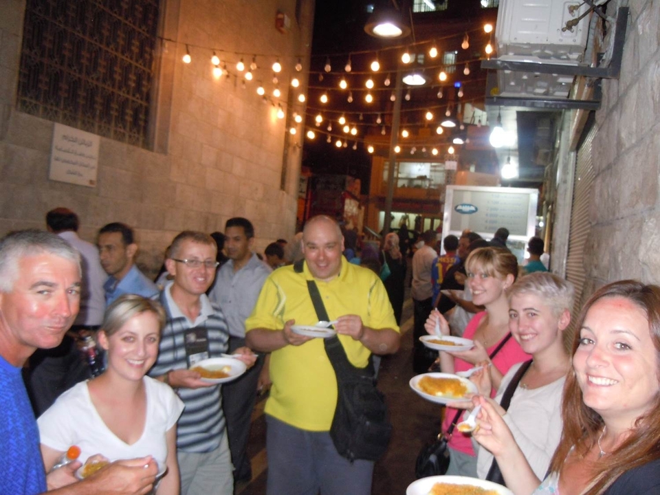 Groupe de personnes dégustant de la nourriture dans un marché de nuit en plein air.