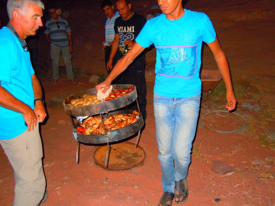 Personnes préparant des aliments sur un gril à charbon de bois en plein air.