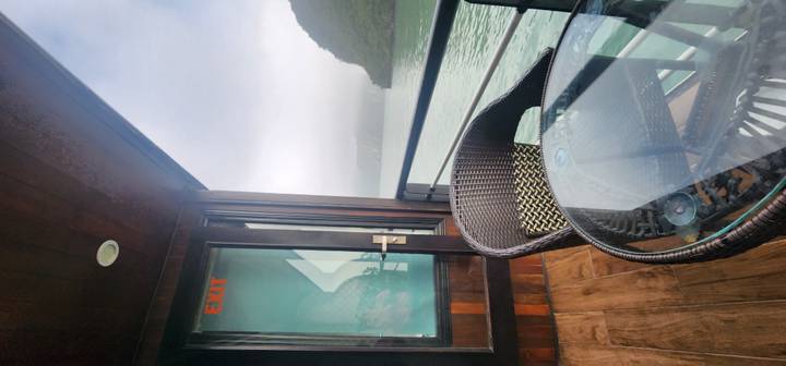 Mist-shrouded limestone islands seen from a cruise balcony in Ha Long Bay.