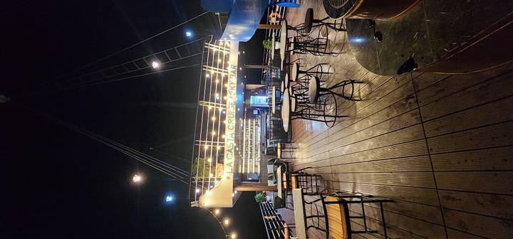 Nighttime upper deck sky bar of a Ha Long Bay cruise ship lit with string lights.