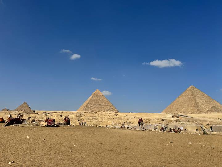 Iconic Great Pyramids of Giza rising from the desert against a clear blue sky.