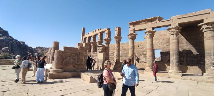 Tour group exploring the stone columns and ruins of Philae Temple on a sunny day.