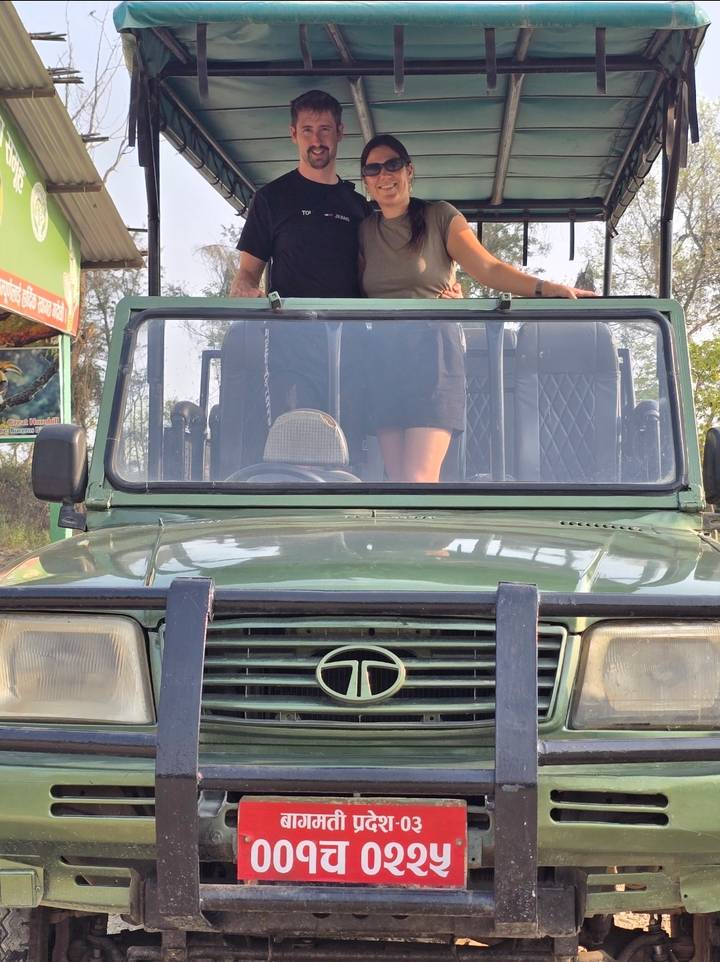 Low-angle shot of an open-top green safari jeep with a passenger standing behind the windshield.