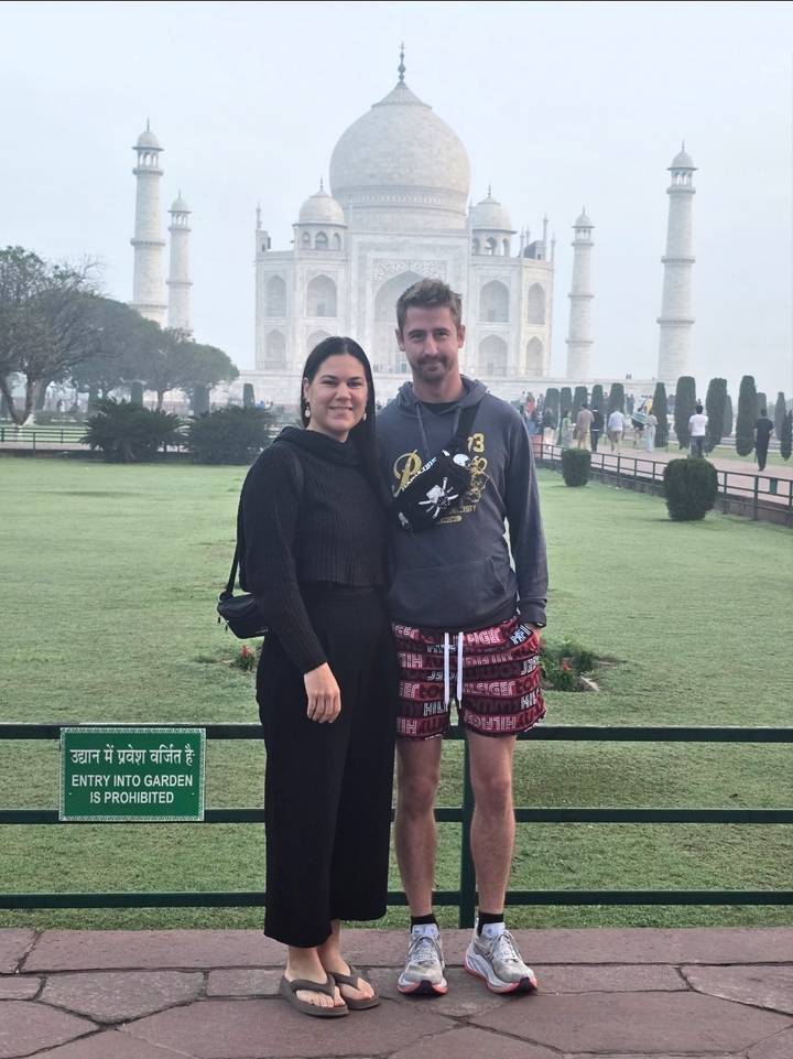 Couple posing in front of the Taj Mahal gardens on a misty morning.