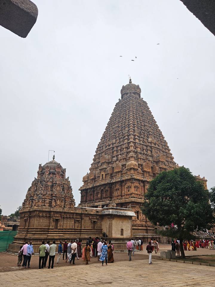Majestic Brihadeeswarar Temple with towering sandstone vimana dominating the cloudy sky.
