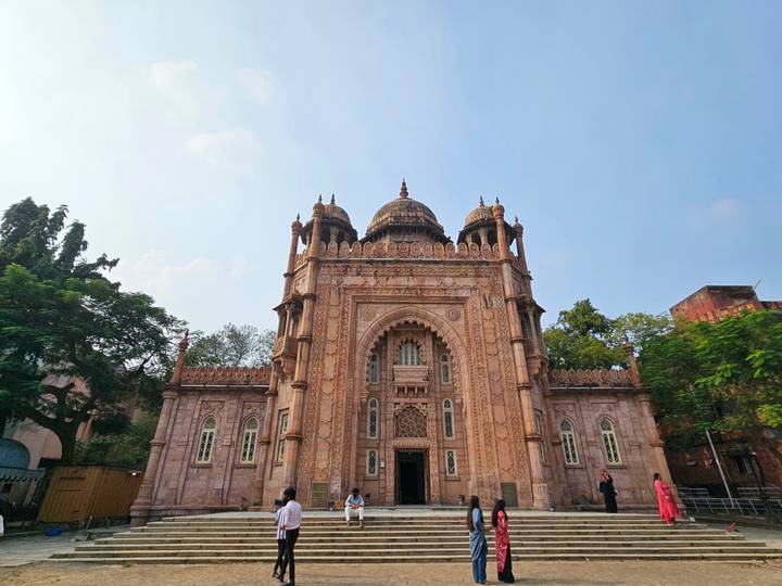 Ornate Indo-Saracenic museum building with pink stone façade framed by trees.