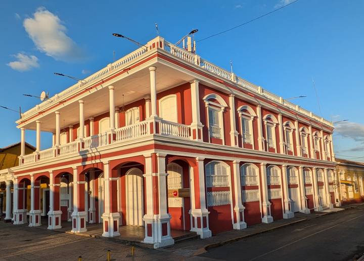 Elegant red-and-white colonial building lit by low golden light.